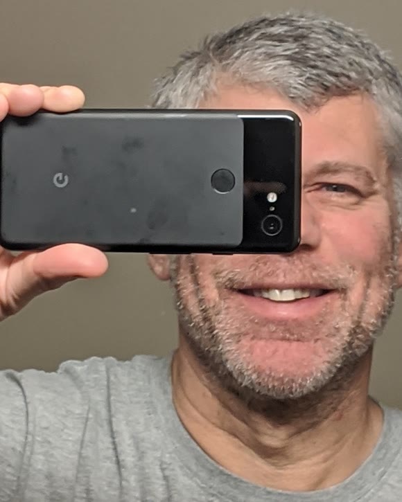 Carl Weiss smiling while holding a phone camera